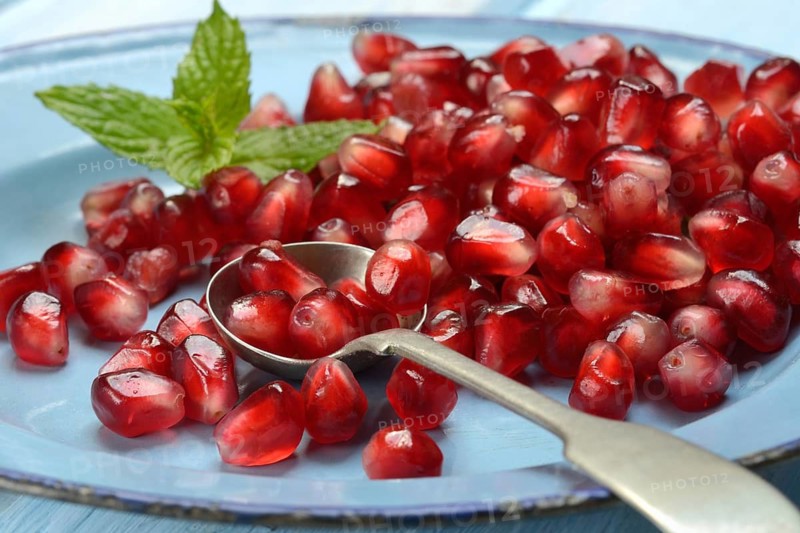 Pomegranate seeds and spoons on plate, Punica granatum