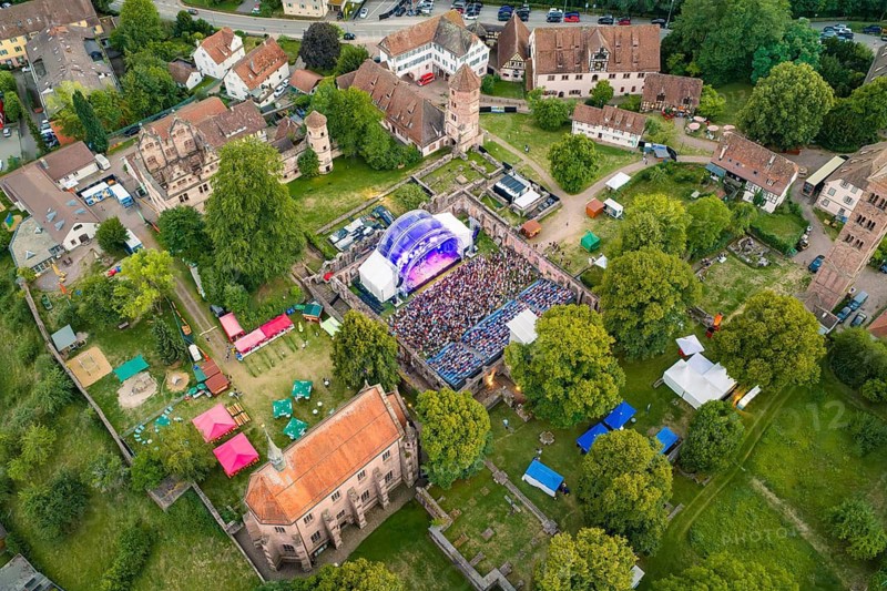 Aerial view of a festival in a historic setting with stage and many visitors surrounded by trees, Calwer Klostersommer Festival, Hirsau Abbey, Calw, Black Forest, Germany