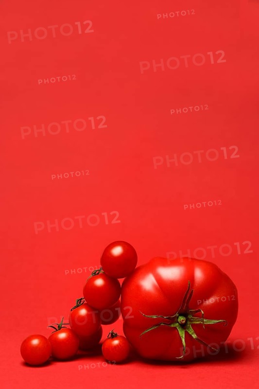 Beef tomato and cherry vine tomatoes with red background