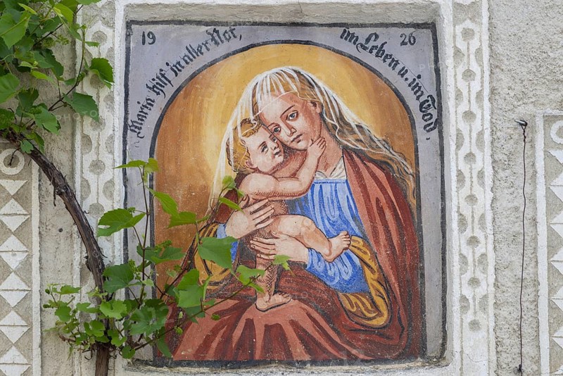 Traditional Marian fresco on a house façade, depicting Mary and Child Jesus, the mural combines religious folk art with the historic townscape of the medieval town, Glurns, South Tyrol, Italy