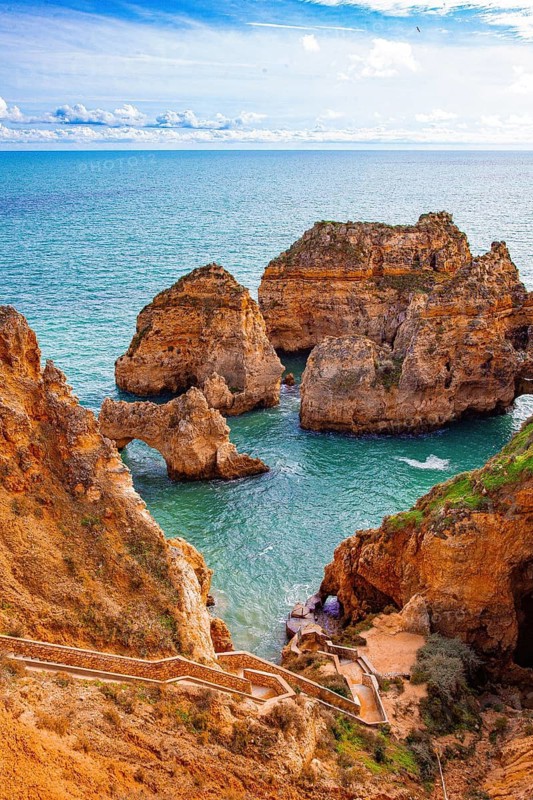 Dramatic rock formations and a rock arch adorn the coast with views of the vast blue sea, rocky coastline of sandstone, rock formations in the sea, Algarve, Lagos, Portugal