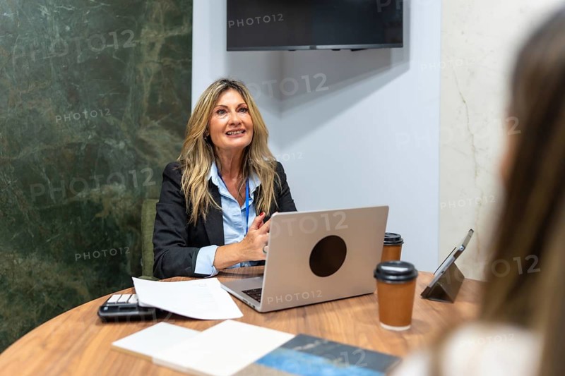 Mature female interior designer discussing project plans with a client in a luxurious showroom, showcasing materials and collaborating on home improvement concepts