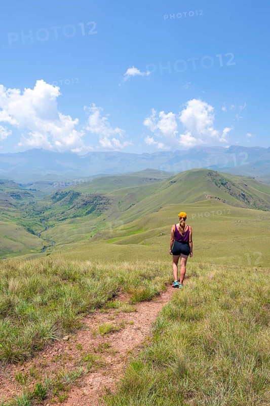 Green hills and valleys, young woman hiking through landscape, Worlds View Hike, Drakensberg, South Africa