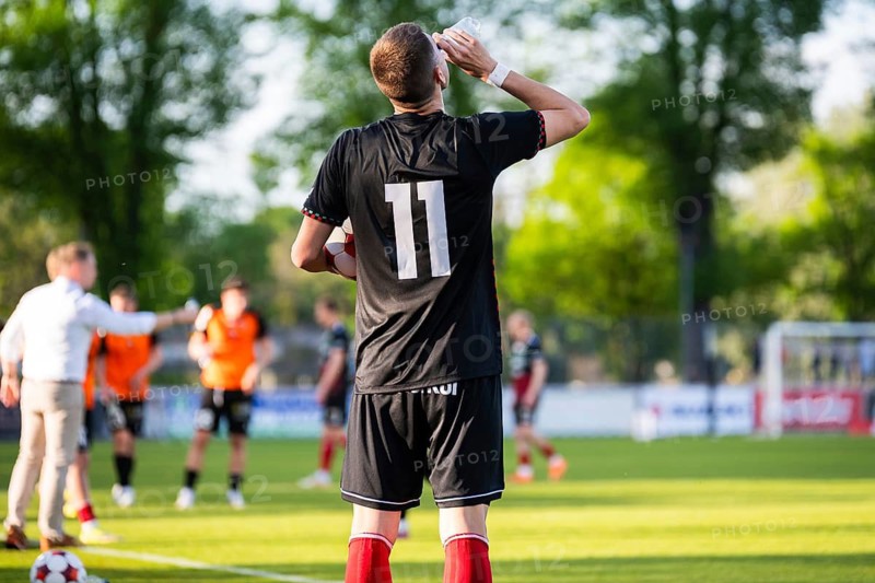 Soccer player wearing number eleven drinking near the sideline during a football match on a sunny day in Glogow, Poland