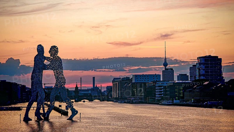 Molecule man, molecule men, sculpture, figures in the water of the Spree against an impressive evening sky and urban environment, sunset, Berlin