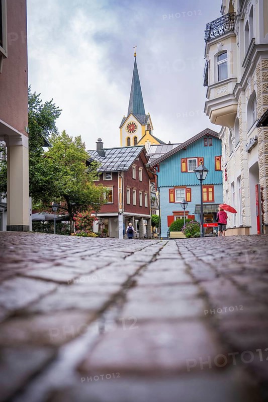Urban line of sight with cobblestones, towering church tower and colorful buildings, Oberstaufen, Allgäu, Bavaria, Germany