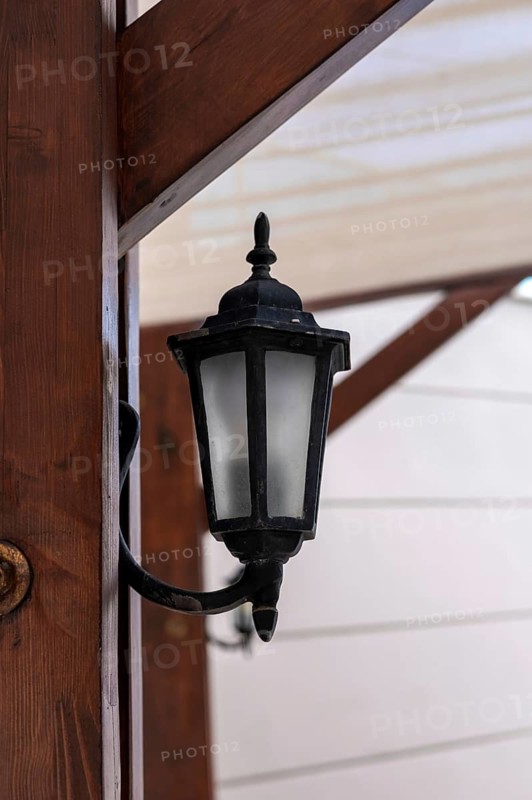 A vintage-style wall lantern is mounted on a wooden beam, providing warm illumination and creating a cozy atmosphere for guests in the evening