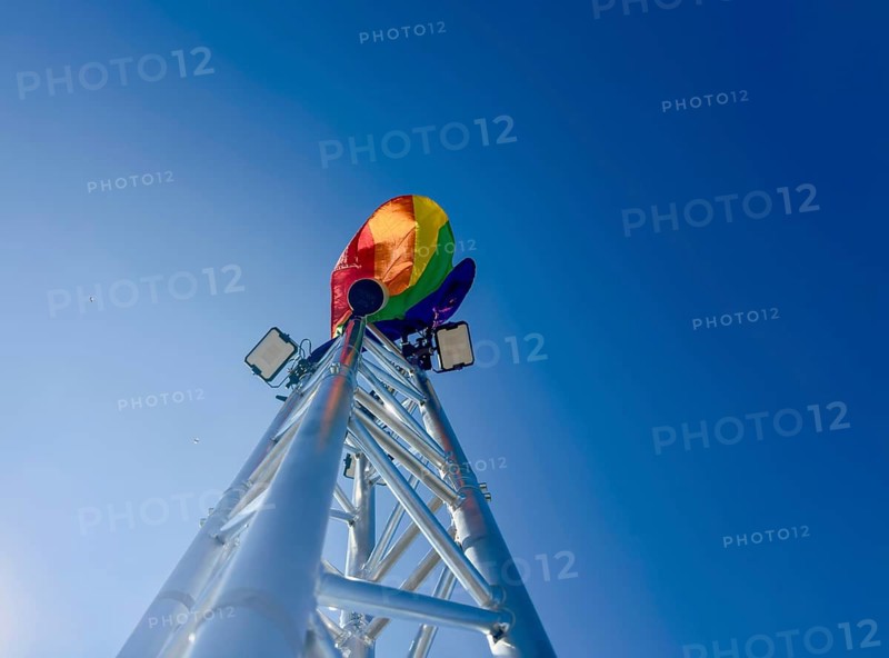 Rainbow flag on a technical truss tower on which LED spotlights are mounted, Berlin, Germany