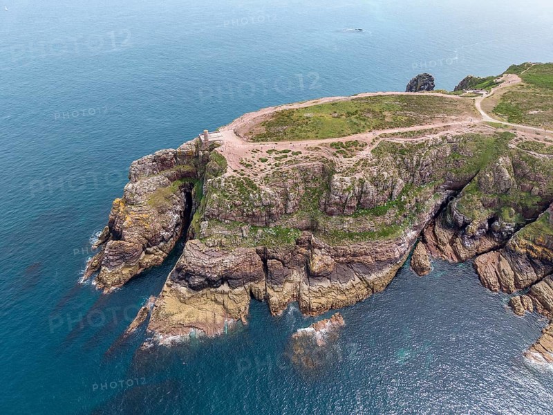 Aerial view of the rocky cliffs at Cap Fréhel with the historic Vauban lighthouse, 17th century Vauban tour, on the heather covered red sandstone cliffs over the Atlantic Ocean, Cap Fréhel, Plévenon, Côtes-d'Armor, Brittany, France