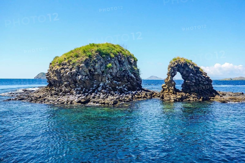 Distinctive rock formation at Batu Bolong dive site means rock with a hole, tourist attraction natural stone arch, Komodo National Park, Flores Island, Indonesia