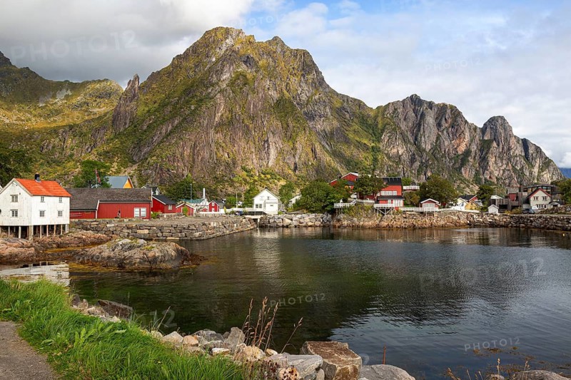 Idyllic bay in a fishing village in front of a huge, steep rock face with traditional Scandinavian houses, Henningsvær, Norway