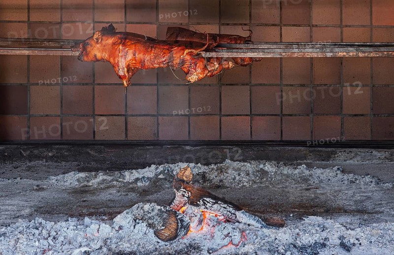 Whole suckling pig traditionally grilled on a skewer over an open wood fire, Majorca, Balearic Islands, Spain