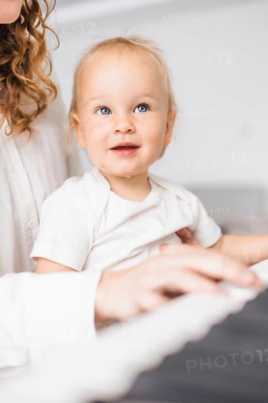 Close-up of a child with curious expression looking up while sitting at a piano