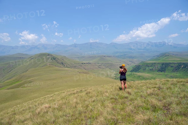 Green hills and valleys, young woman photographing landscape, Worlds View Hike, Drakensberg, South Africa