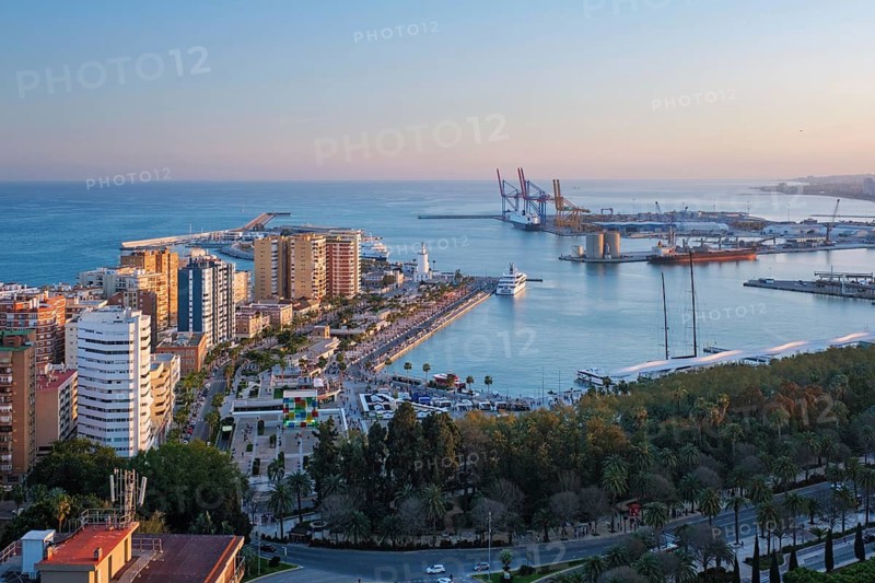 Elevated golden hour view of Muelle Uno and the Port of Malaga in Spain, with La Farola lighthouse, marina, waterfront promenade and Mediterranean Sea