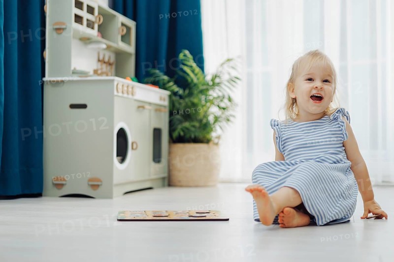 Child girl toddler enjoys a colorful puzzle on the floor while surrounded by soft light and greenery