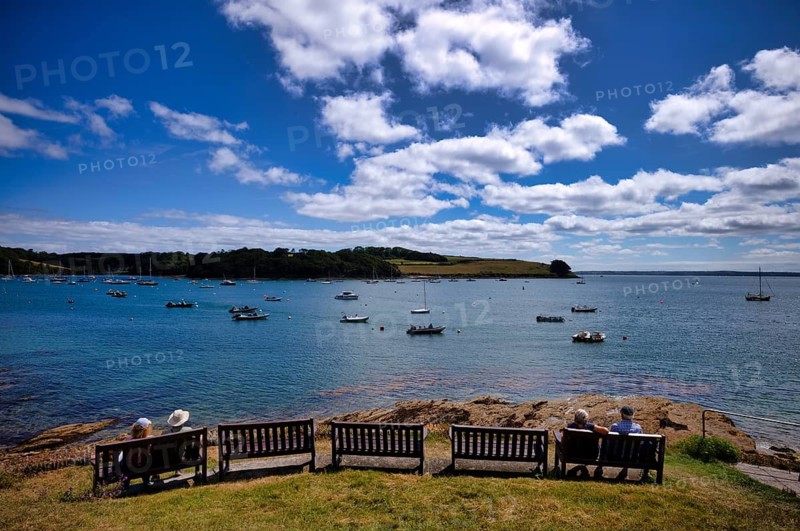 People sitting on a bench in a park and looking at boats in the harbor, sea, clouds, St Mawes, Cornwall, England, Great Britain