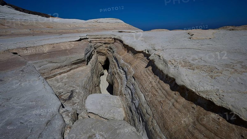 Erosion cracks in dry rock under clear blue sky, white volcanic strata, bizarre white rocks in the sea, Little Sarakiniko, Kioni Beach, Kioni, Kimolos Island, Cyclades, Greek Islands, Greece