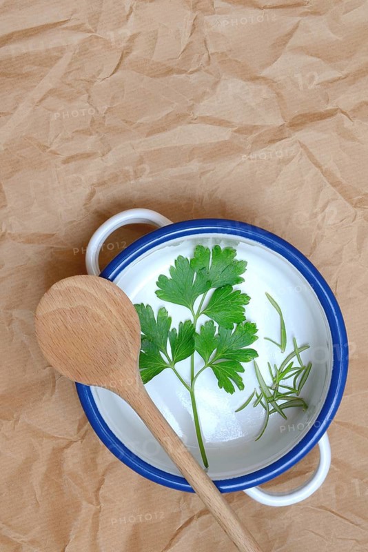 Parsley and rosemary with cooking spoon on pot