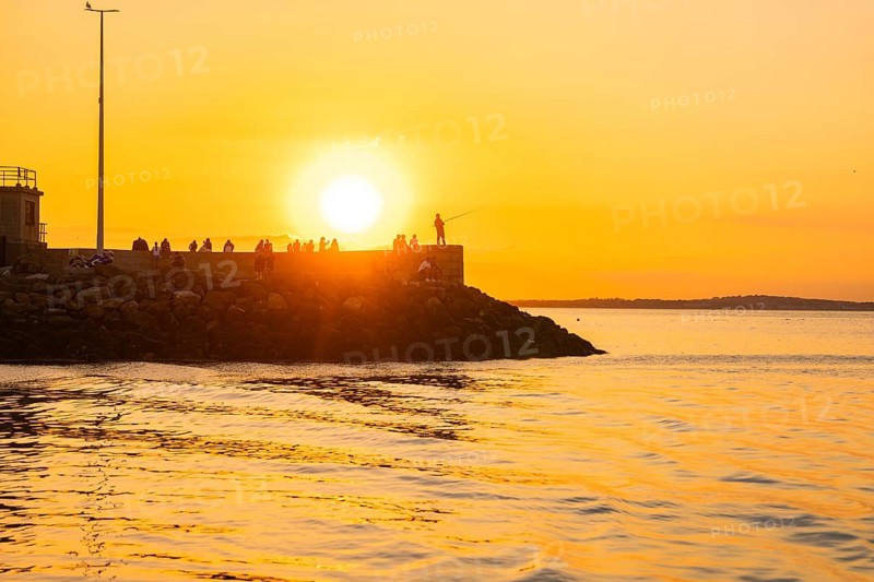 People on a pier in sunset light, fishing on the horizon, Howth, Ireland