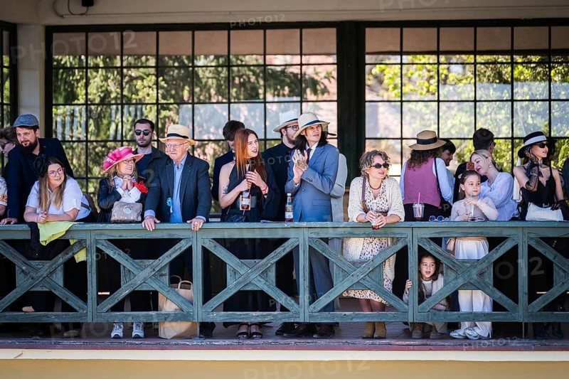WROCLAW, POLAND - MAY 1, 2026: Horse race track WTWK Partynice. Crowd of elegant spectators wearing hats and formal clothes watching a horse race from a wooden gallery