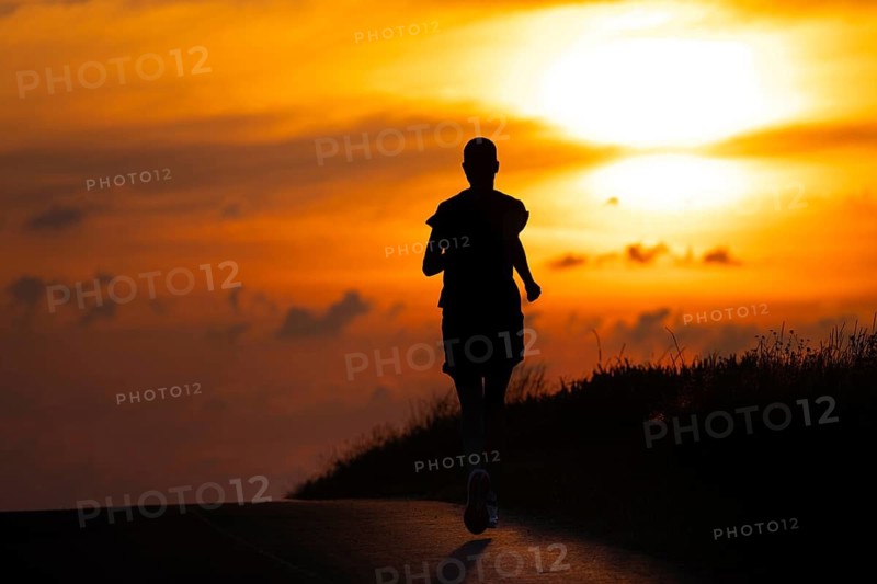 A female jogger runs along a Feldberg near Frankfurt am Main in the morning just after sunrise, Frankfurt am Main, Hesse, Germany