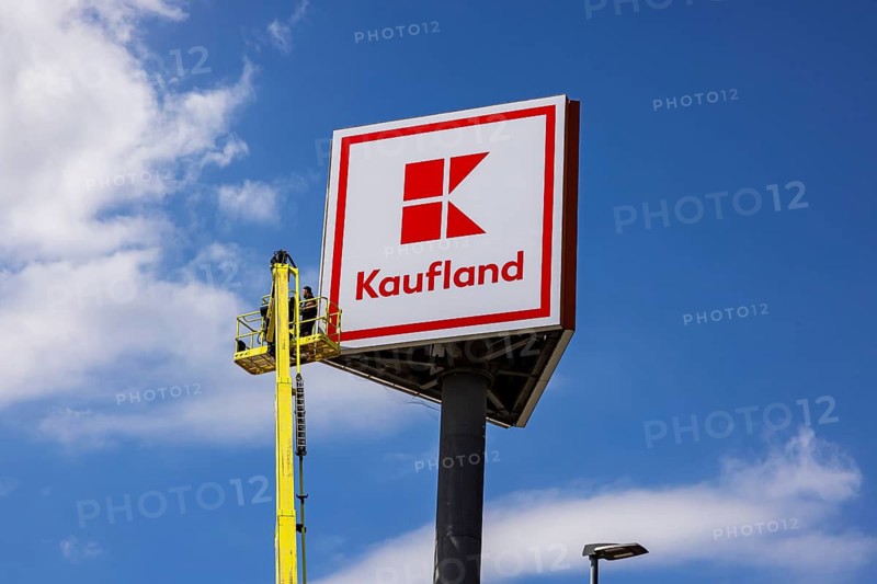 Advertising pylon at the Kaufland supermarket. Workers are renewing the logo by means of a climber. Zimmern ob Rottweil, Baden-Württemberg, Germany