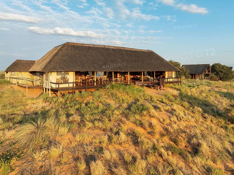 The main building of the Ta Shebube Rooiputs Lodge in the Kalahari Desert during the rainy season with green vegetation. Drone shot. Kgalagadi Transfrontier Park, Botswana