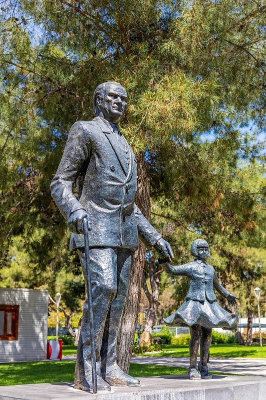 Antalya, Turkiye - April 14, 2025: Statue of Mustafa Kemal Ataturk holding childs hand in public park in Turkey. Monument symbolizing leadership, national identity, and future of younger generations