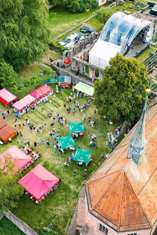 Summer festival from above with colorful tents, a stage and a crowd in daylight, Calwer Klostersommer Festival, Hirsau Abbey, Calw, Germany