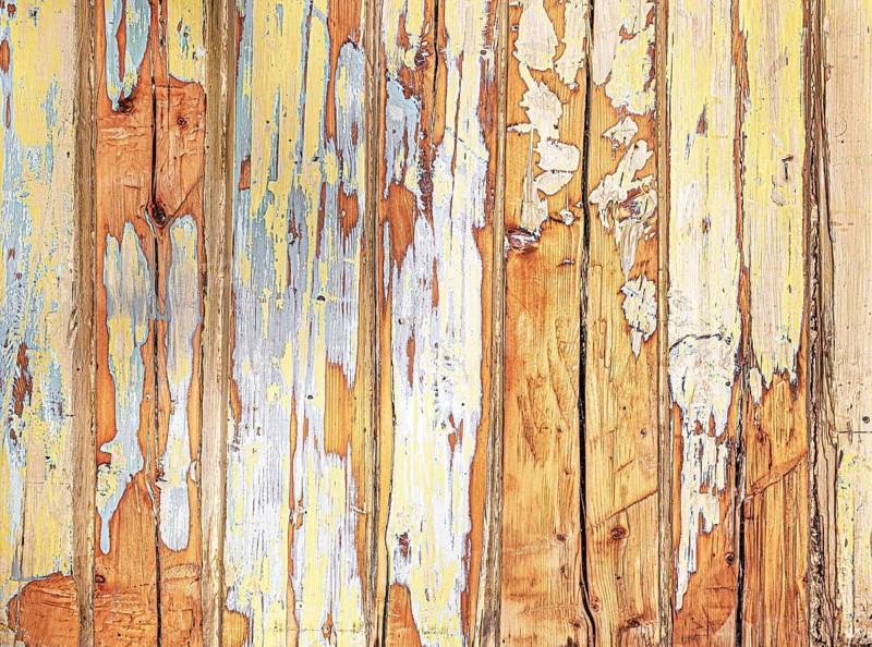 Abstract close-up of weathered wooden wall with peeling yellow, white, blue and orange paint