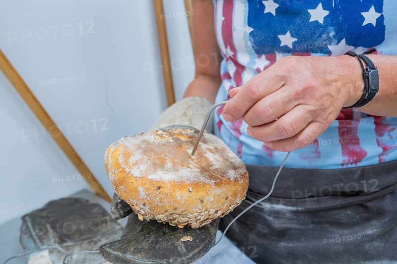 A woman takes a temperature measurement on a loaf of bread covered with oats, bake bread, Haselstaller Hof, Gechingen, Calw district, Germany