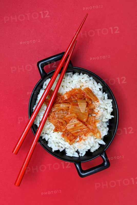 Kimchi, fermented vegetables on rice in bowl with chopsticks