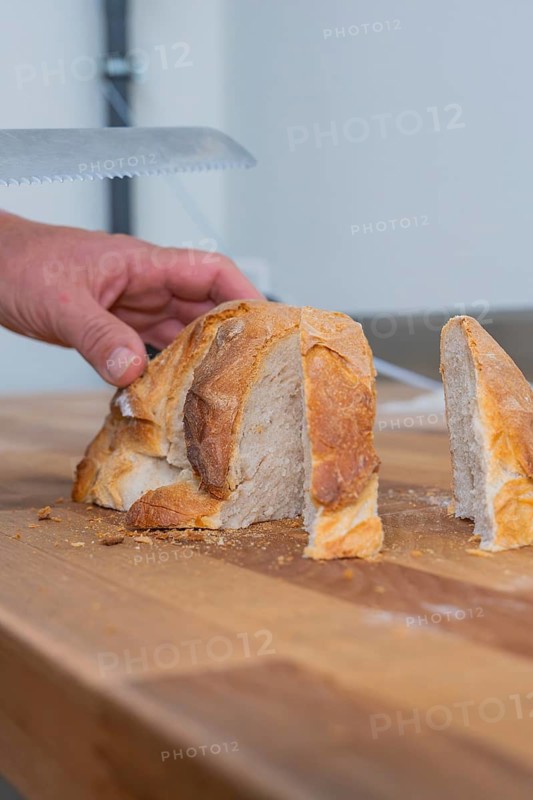 A hand cuts a loaf of bread with a clean slice on a wooden board, bake bread, Haselstaller Hof, Gechingen, Calw district, Germany