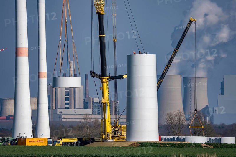 Construction site of the new Bedburg 3 wind farm, on recultivated open-cast mining site, 9 wind power plants with an output of 60 megawatts are newly built, installation of the wind turbine tower, in the background the Neurath lignite power plant, operated by RWE and the city of Bedburg, North Rhine-Westphalia, Germany