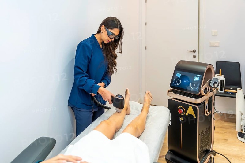 Beautician using a modern laser device to remove unwanted hair from a woman's leg in a comfortable aesthetic clinic or medical spa setting, symbolizing beauty, technology, and skin care