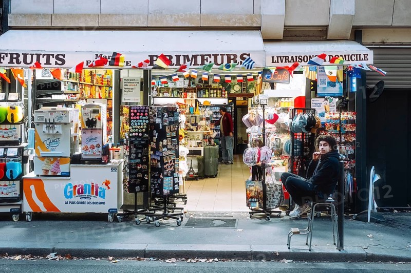 Lively street scene at a French general store with extensive outdoor displays and numerous advertising signs, Paris, Île-de-France, France