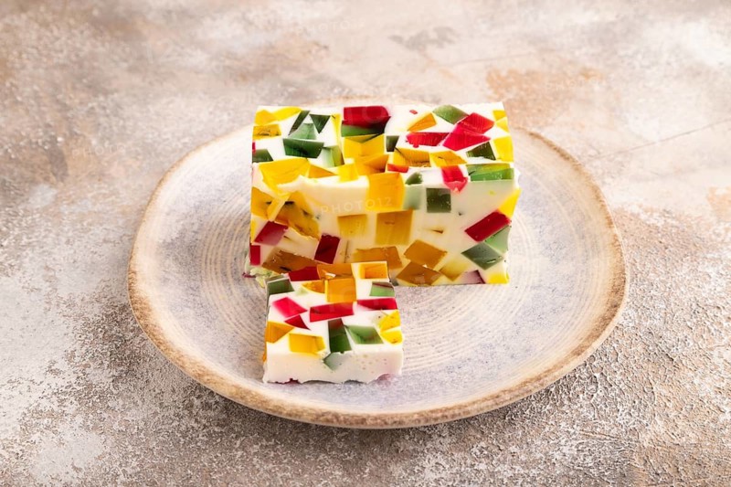 Colored Fruit and milk jelly on brown concrete background, side view, close up, minimalism