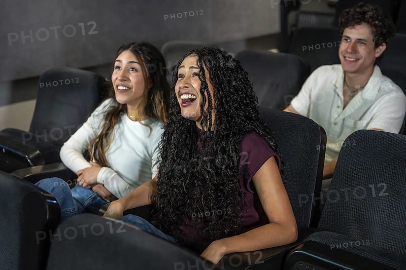 Friends laughing and enjoying a movie at the cinema, sharing a moment of leisure and entertainment