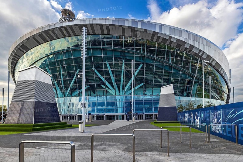 Sunlight catches the curved glass and steel facade of Tottenham Hotspur Stadium on White Hart Lane, London, England, United Kingdom