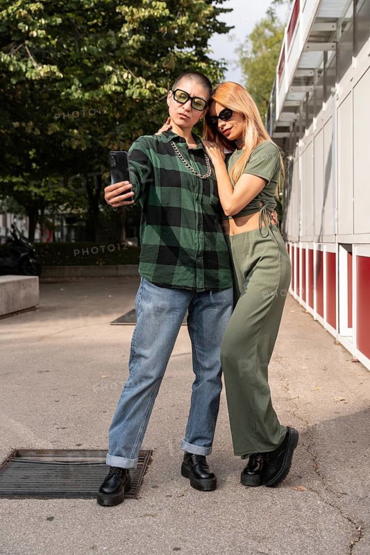 A Colombian lesbian couple captures a selfie, embracing in an urban environment, reflecting love, diversity, and the embrace of LGBTQIA+ identity and culture