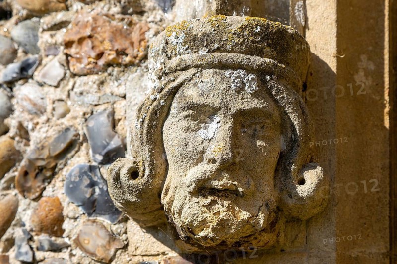 Weathered medieval carved stonework head of a king, church of Saint Peter, Theberton, Suffolk, England, UK