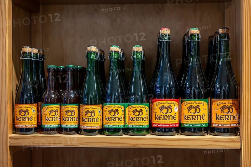 Numerous green glass bottles of Breton cider kerné with characteristic yellow-orange labels are neatly lined up in a specialty shop, souvenir shop and delicatessen, Roscoff, Finistère department, Brittany, France