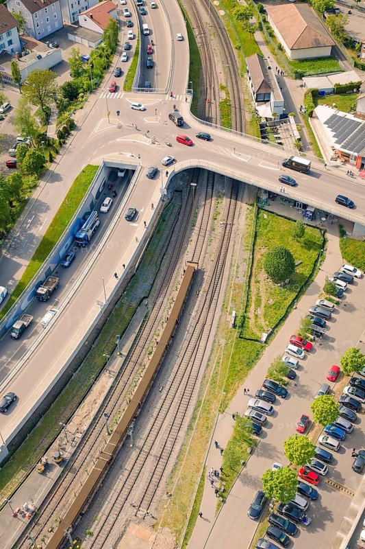 Aerial view of a road junction with passing cars next to railroad tracks, Leonhard Weiss construction site for the renovation of the station and construction of the overhead line, Waldshut, Germany
