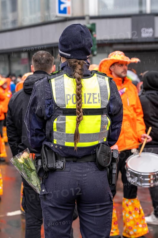 Rose Monday procession in Düsseldorf, emergency services, secure, accompany the move, policewoman with bouquets of flowers, Strüsschen, in some cases heavy rain, North Rhine-Westphalia, Germany