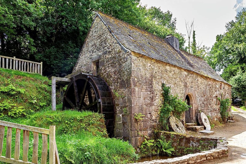An old mill in the countryside with a large water wheel and moss-covered stones, The mill of the Écomusée des Monts d'Arrée in Brittany
