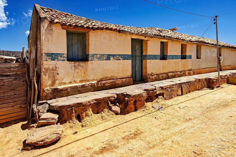 Village street with a long, one-story building with rustic façade under clear skies, settlement and villages in the Caatinga of Pernambuco and Bahia in Brazil