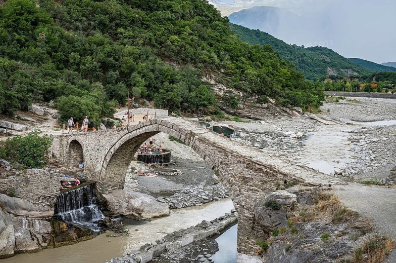 BENJA, ALBANIA - JULY 1, 2026: Historic Ottoman stone arch bridge spanning over a river in a rocky mountain canyon near Benja thermal springs in Albania