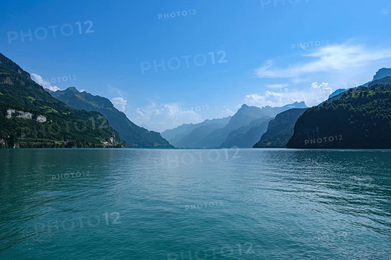 View of Lake Lucerne surrounded by mountains under a clear blue sky, fountain, Canton of Schwyz, Switzerland