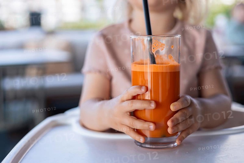 Close-up of glass of fresh carrot juice in child hands